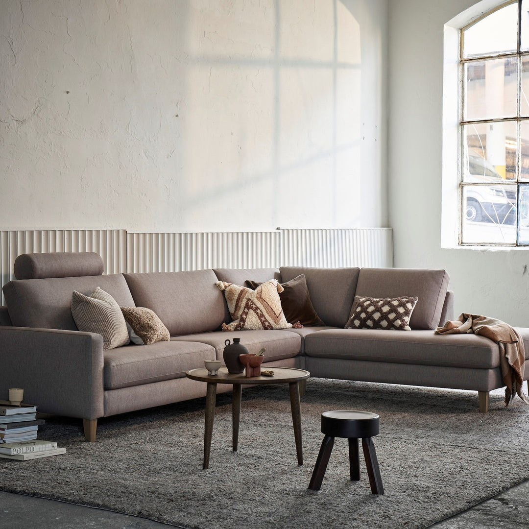 Scandinavian Touch hjørnesofa i gråbrun i lys loftstue med grått teppe og sofabord.
