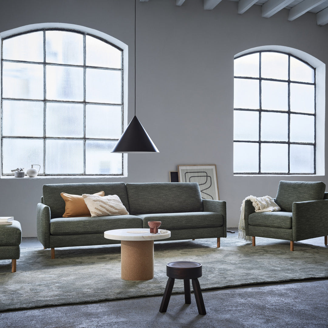 Scandinavian Touch stol i mørk grønn med matchende sofa i lys industristue med buevinduer.