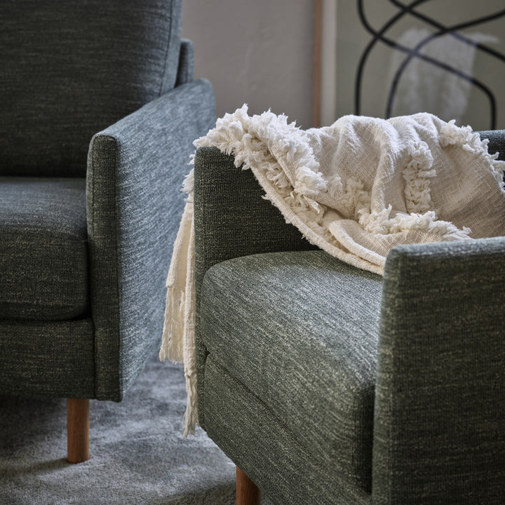 Scandinavian Touch 4-seter sofa i grågrønn chenille med hvitt frynsepledd på grått teppe