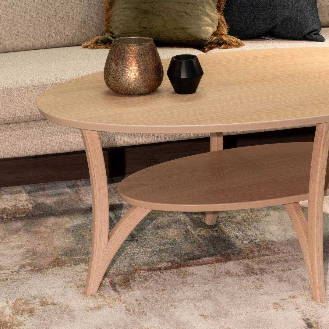 Kleppe Spinell sofabord i lakkert eik, ovalt med hylle foran beige sofa