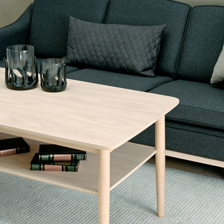 Kleppe Tind sofabord i hvitpigmentert eik med hylle foran mørk grå sofa