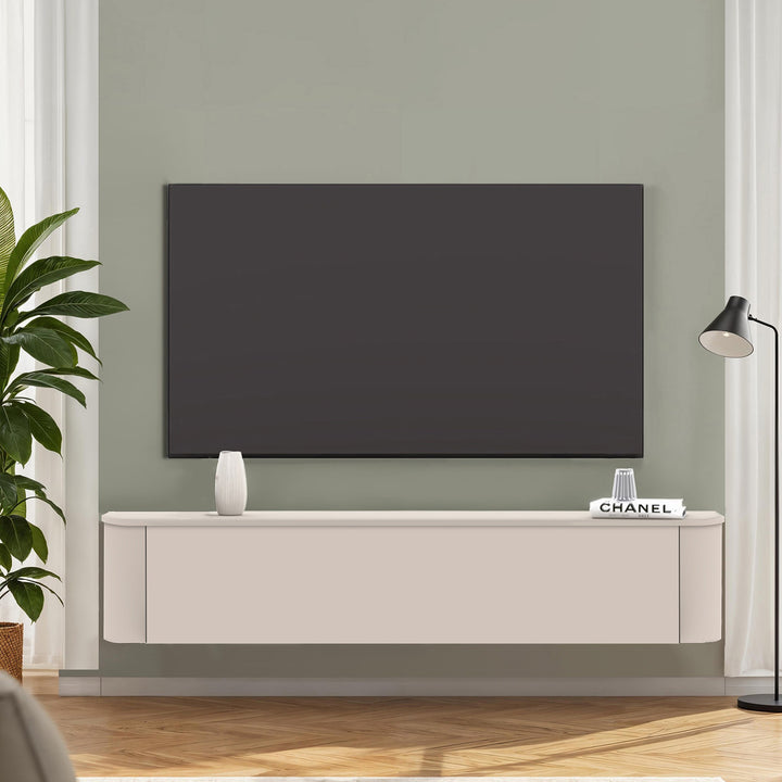 Lido TV-benk i kremhvit, veggmontert under TV mot salviegrønn vegg med plante og gulvlampe.