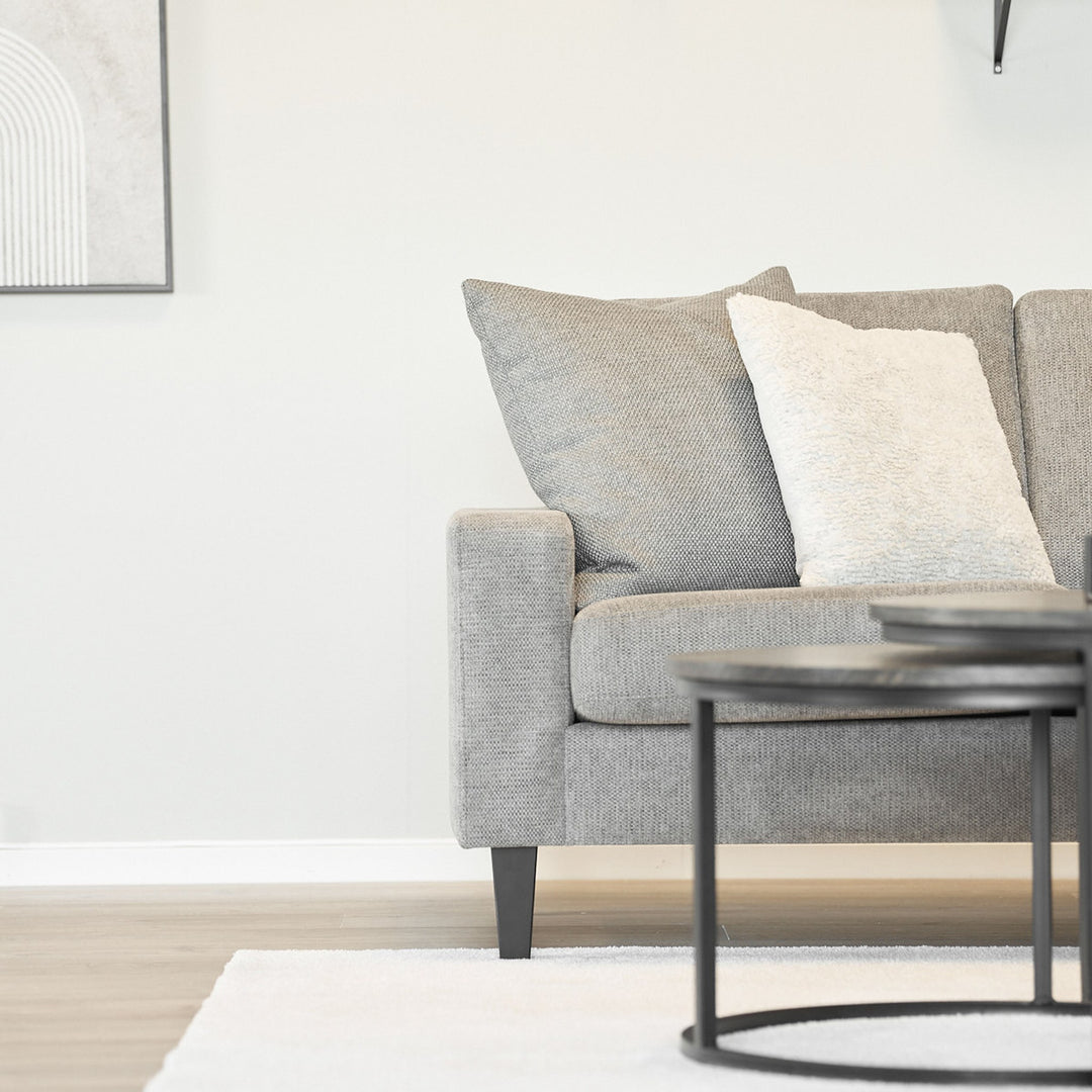 Lone Sensation teppe i cremehvitt foran grå sofa med sorte sofabord.