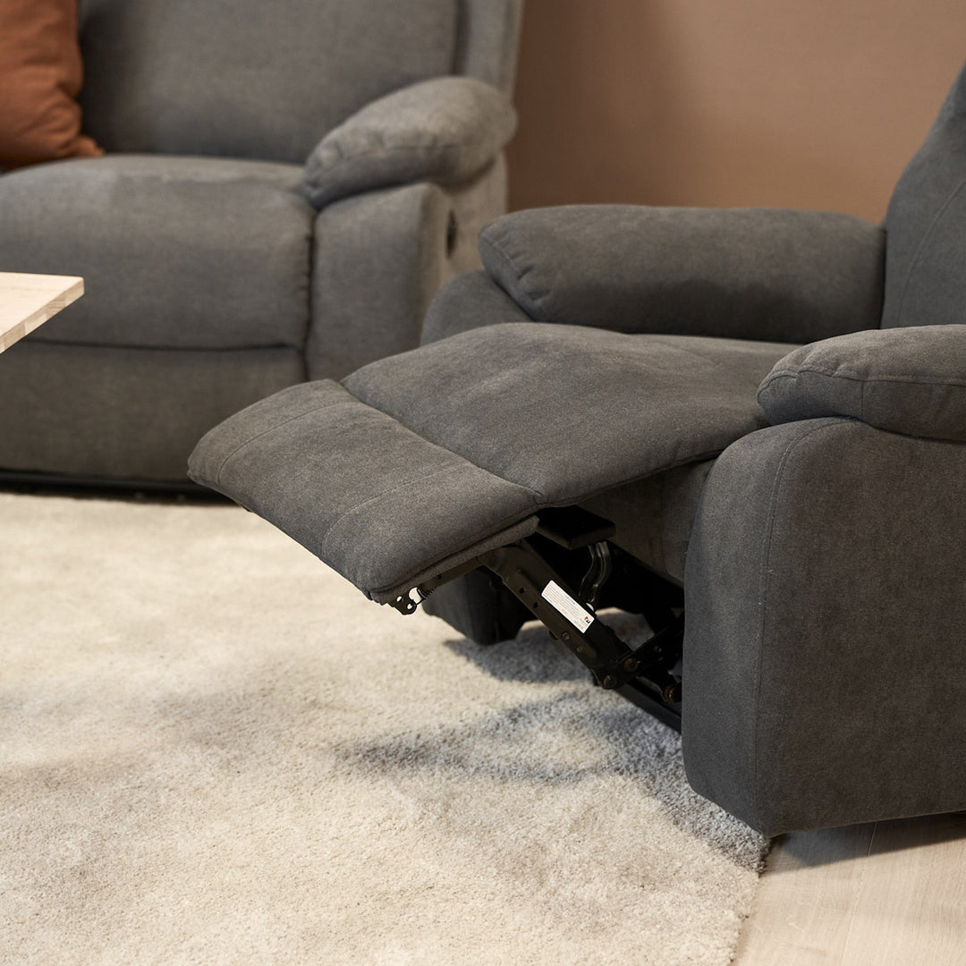 Mora reclinerstol i mørk grå med utfelt fotstøtte ved grå sofa.