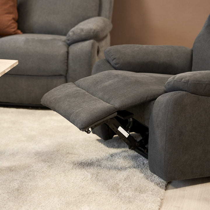 Mora reclinerstol i mørk grå med utfelt fotstøtte ved grå sofa.