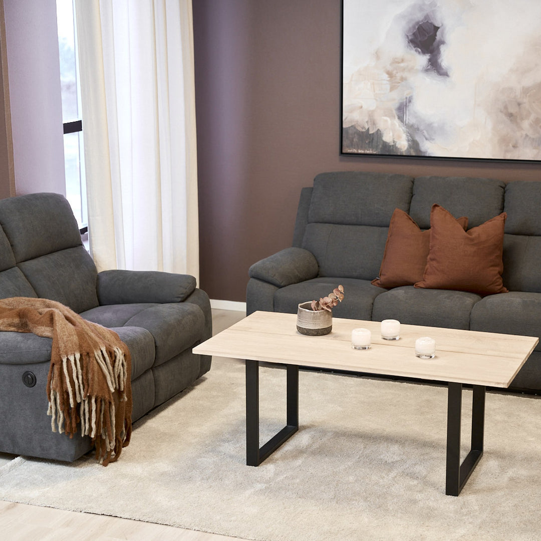 Mora reclinersofa i mørk grå i stue med sofabord, reclinerstol og veggbilde.