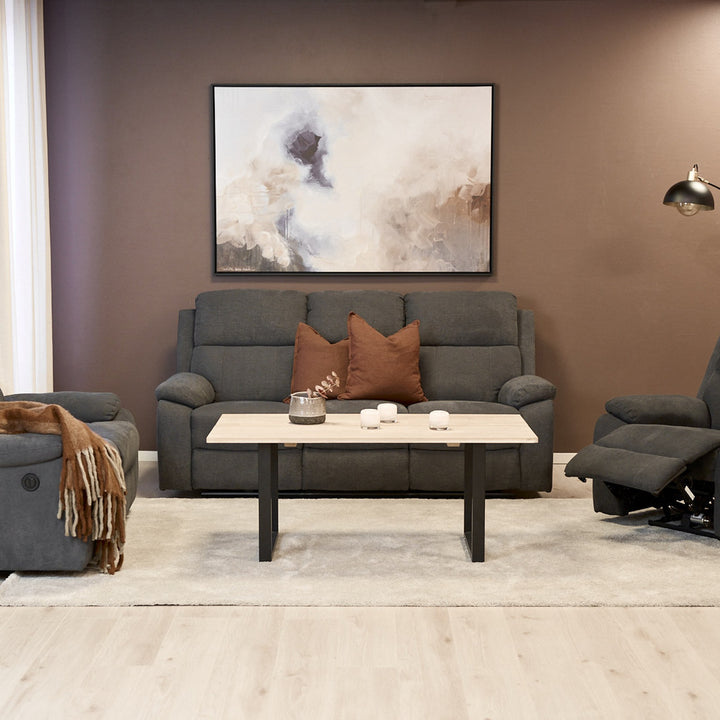 Mora reclinersofa i mørk grå i stue med sofabord, reclinerstol og veggbilde.