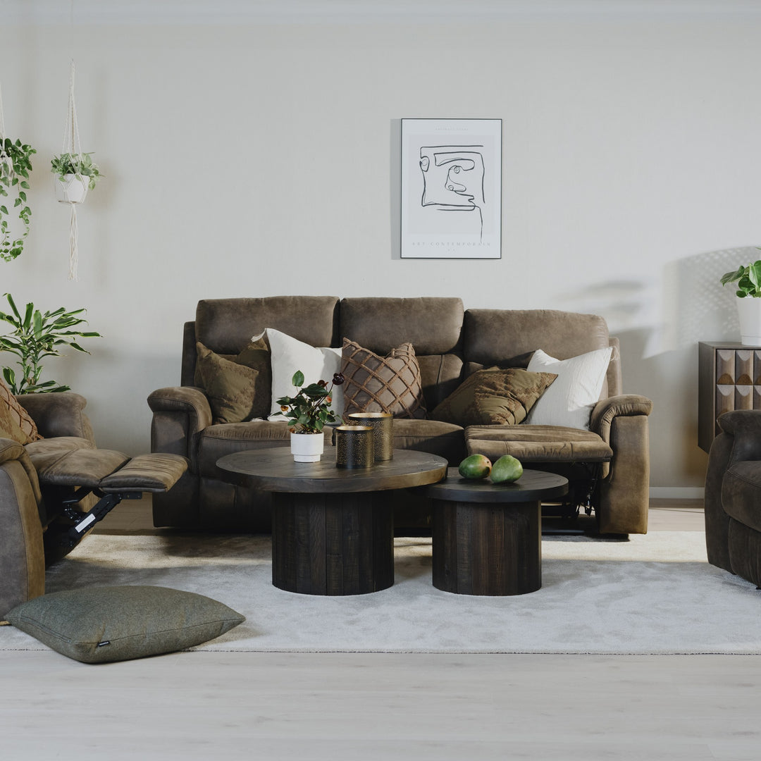 Mayfield stol i gråbrunt stoff i stuemiljø med sofa, mørke rundbord, planter og veggkunst