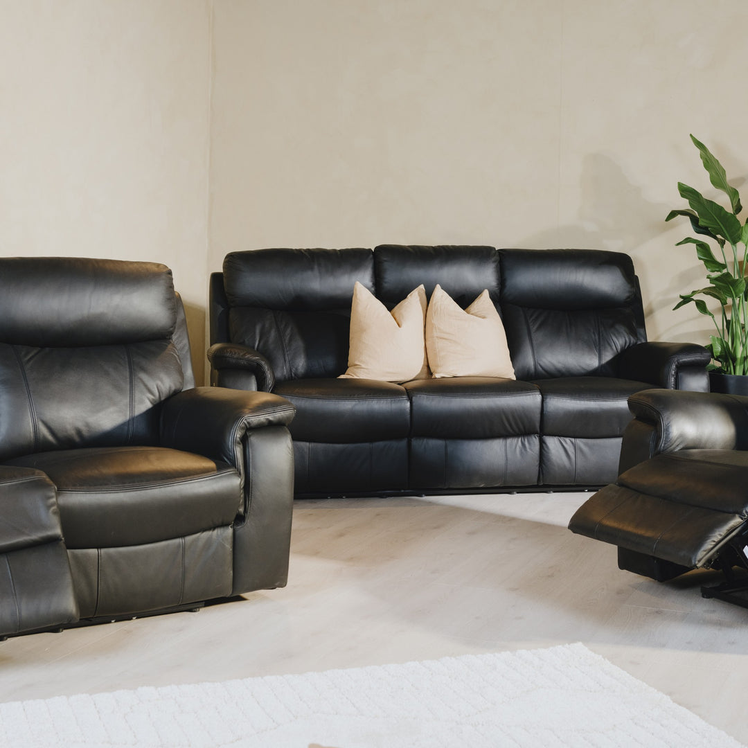 Mayfield sofa i sort skinn med recliner-funksjon i lyst rom med beige puter og grønn plante