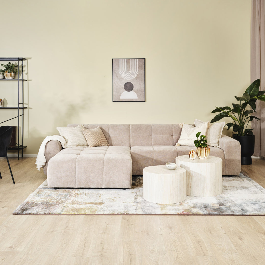 Columbia hjørnesofa i sandfarget stoff med sjeselong i lys stue med travertinbord og potteplante