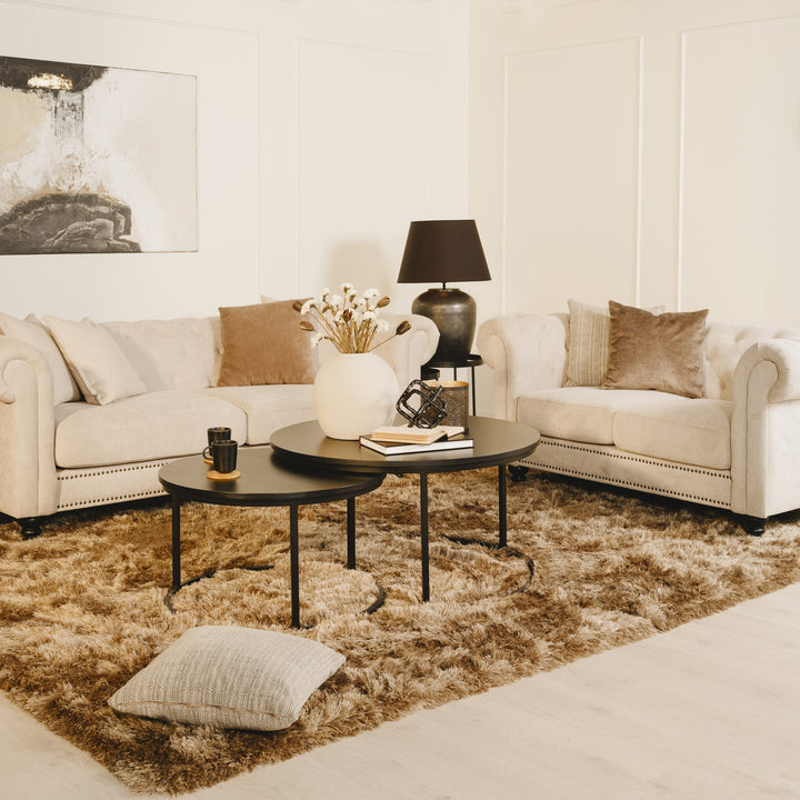 Charlietown sofa i kremhvit stoff med chesterfield-søm, sorte sofabord og lodden teppe