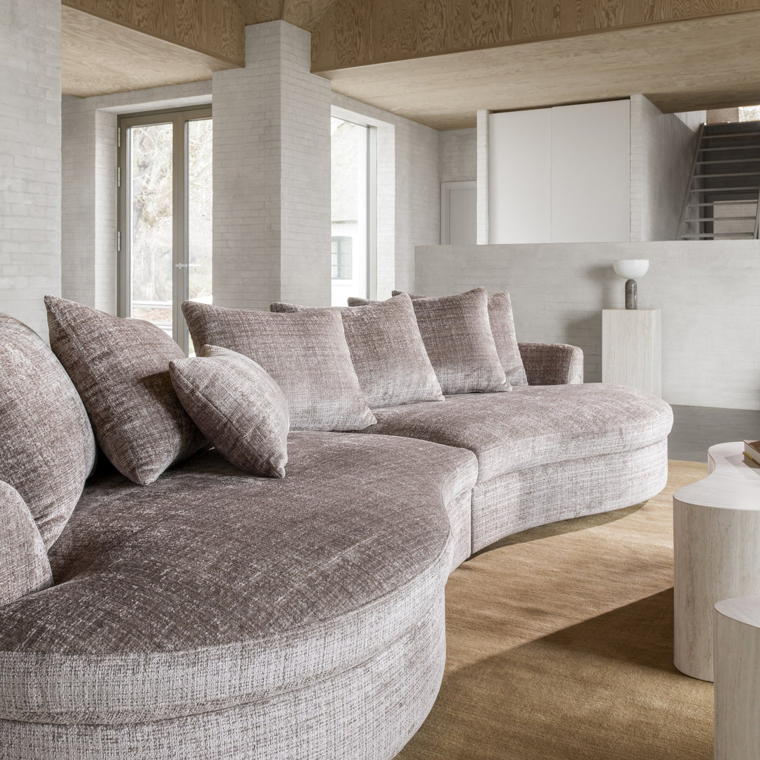 Cordova buet sofa i gråbrun chenille i lyst loftsrom med flere puter og hvite sidebord.