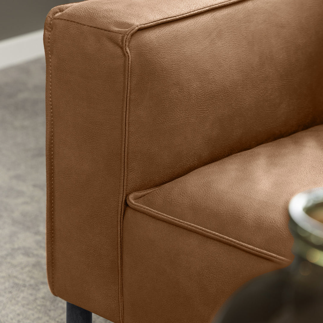Montebello sofa i konjakkfarget skinn, nærbilde av armlene og svart ben.