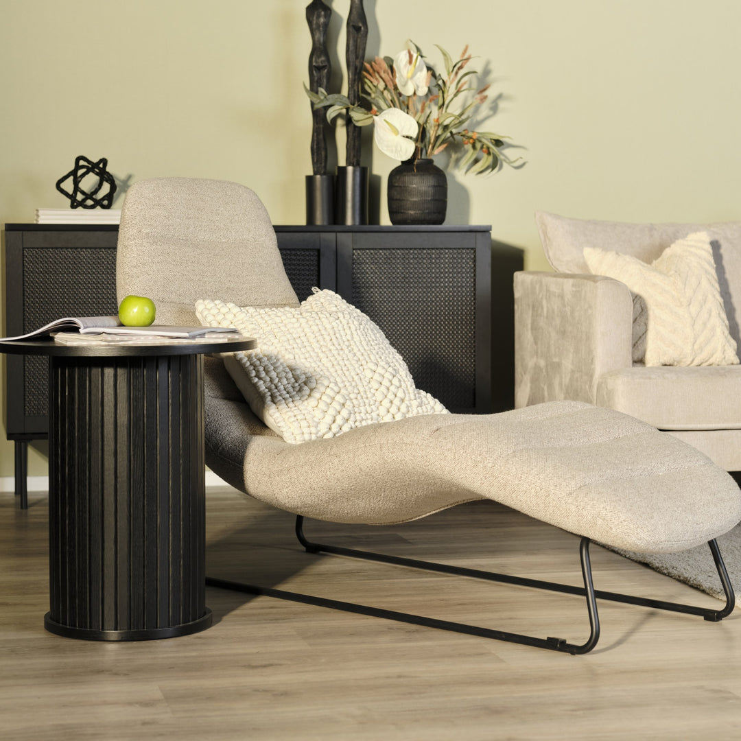 Chaplin loungestol i sandfarget bouclé i stue med sort sidebord, rottingskjenk og beige sofa