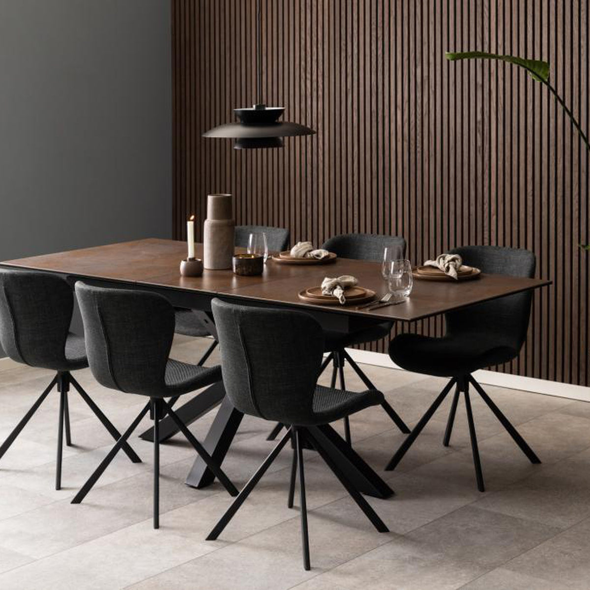 Heaven spisebord med rustbrun plate i spisestue med sorte stoler og panelvegg