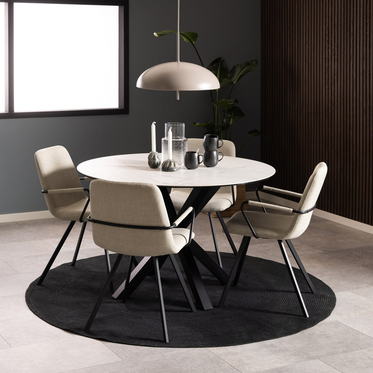 Earth spisebord med hvit keramikkplate og sort kryssfot, med beige stoler på mørkt teppe