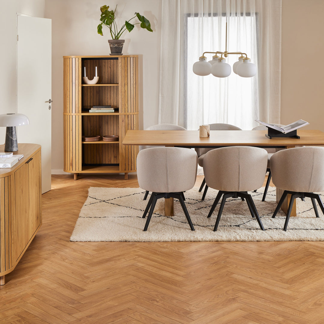 Colima spisebord i eik med beige stoler, i lyst rom med ribbeskap og fiskebensparkett