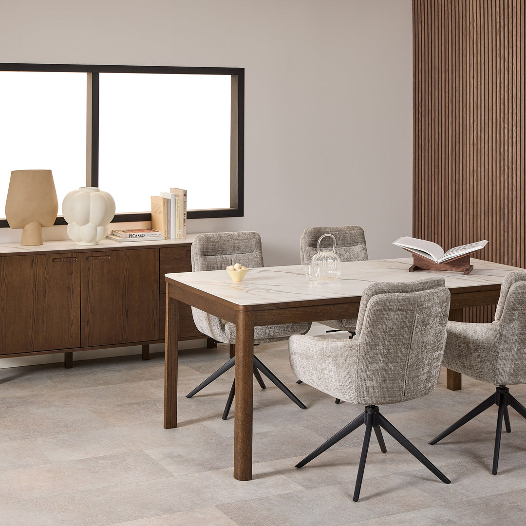 Hampton spisebord med hvit marmorplate og brune treben, omgitt av beige svingstoler ved mørkt sidebord