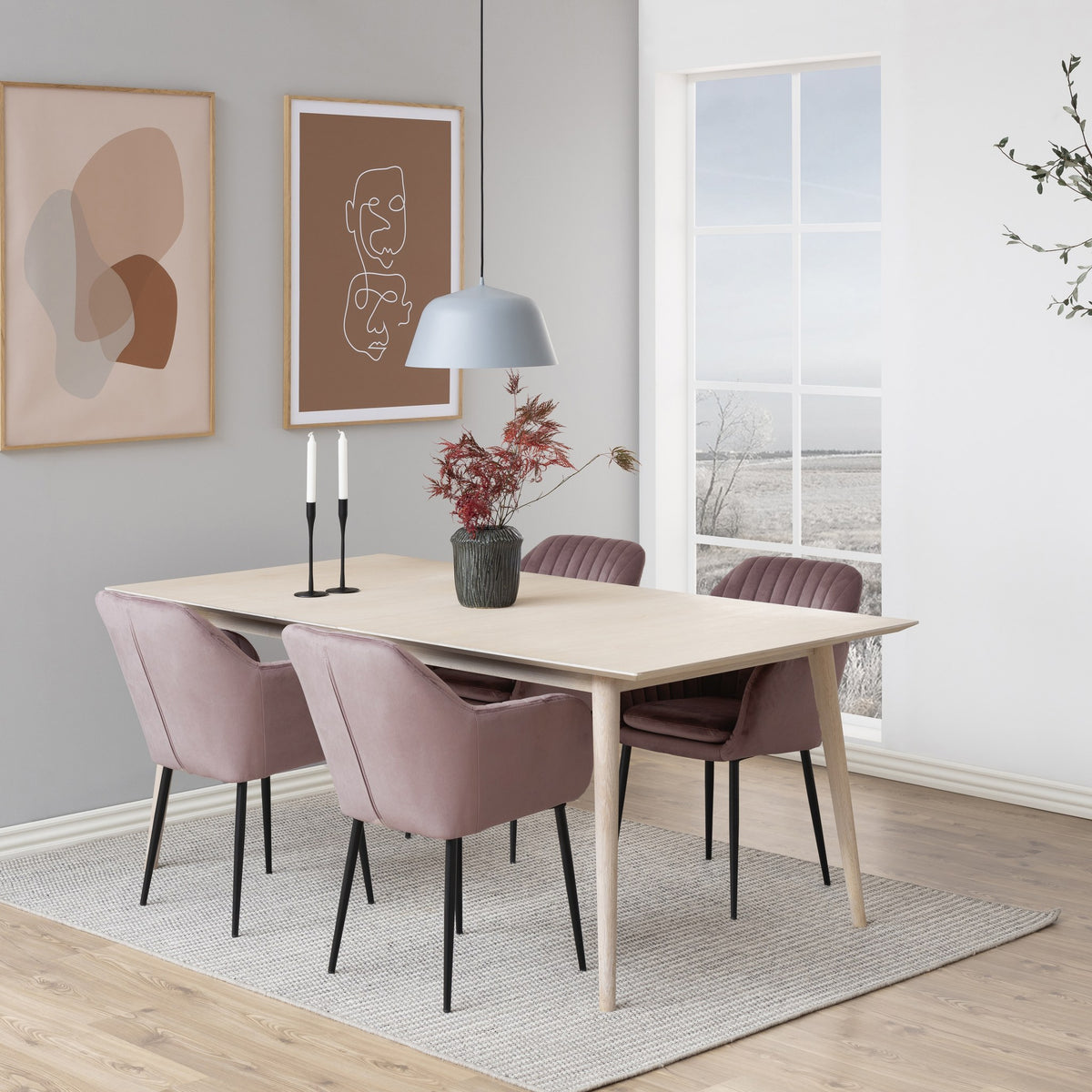 Emilia spisestol i støvet rosa velur med svarte ben, ved lyst trebord med pendel og veggkunst