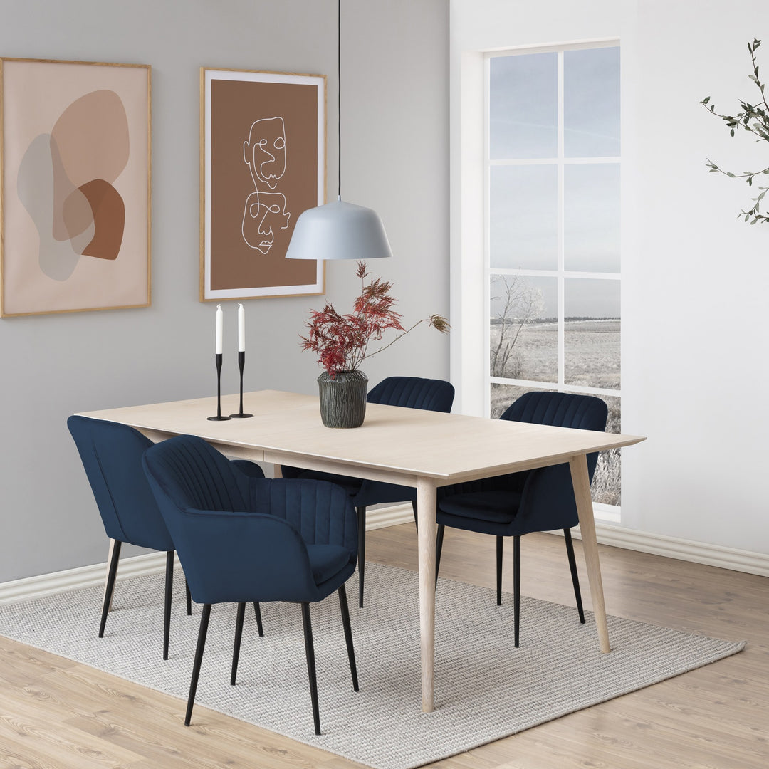 Emilia spisestol i blå velur ved lyst spisebord med lysestaker og vase