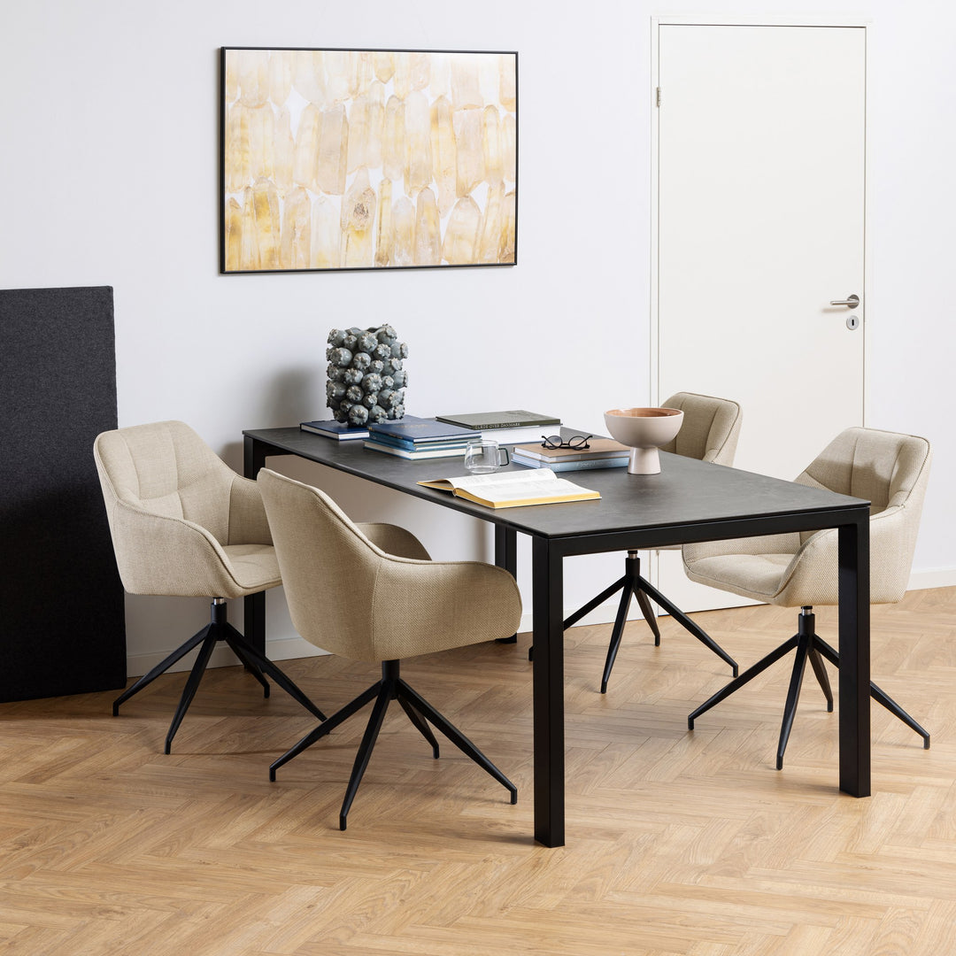 Brenda spisestol i beige stoff med svarte dreieben, fire stk rundt sort spisebord under abstrakt bilde