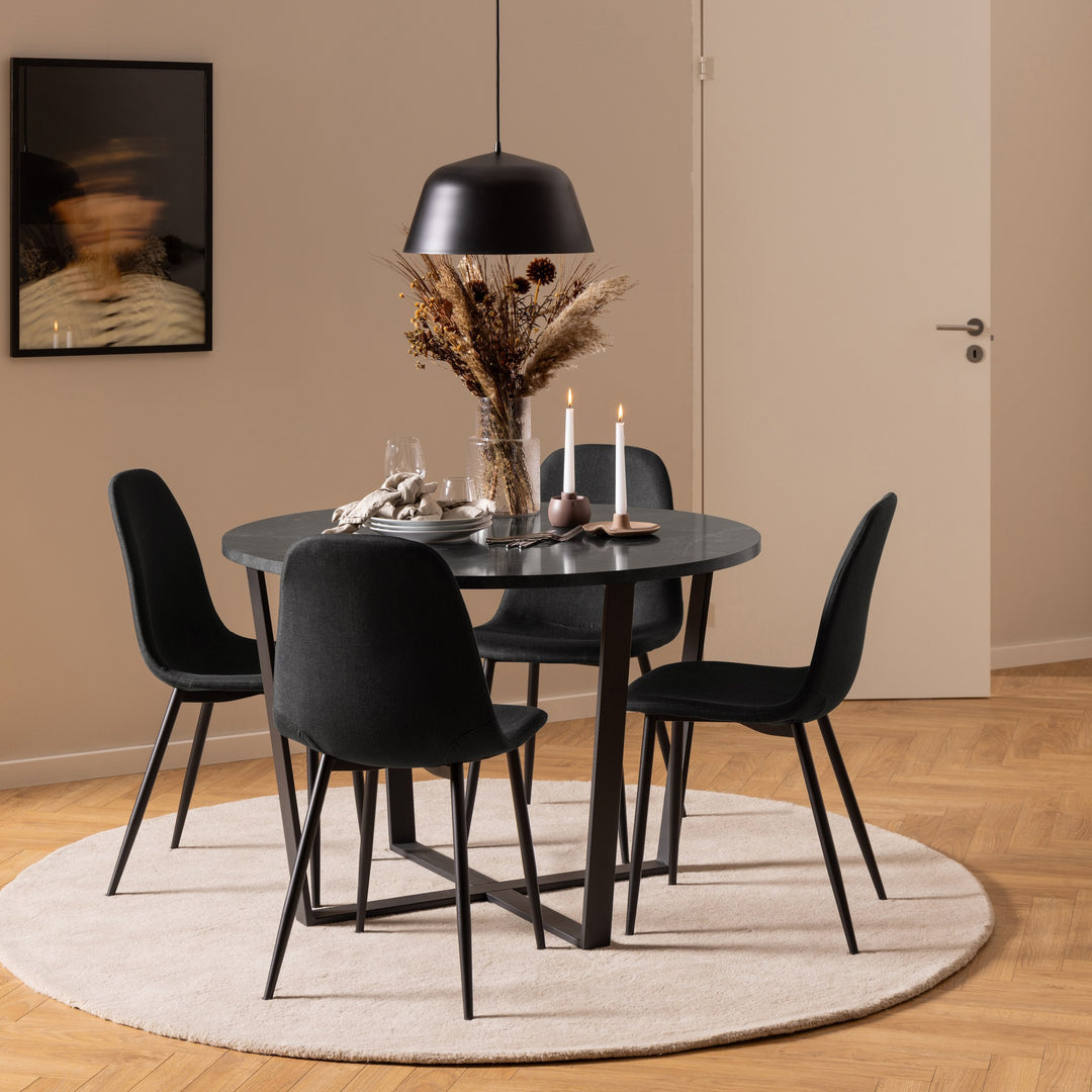 Celia spisestoler i sort rundt sort spisebord med tørkede blomster, beige teppe og sort taklampe