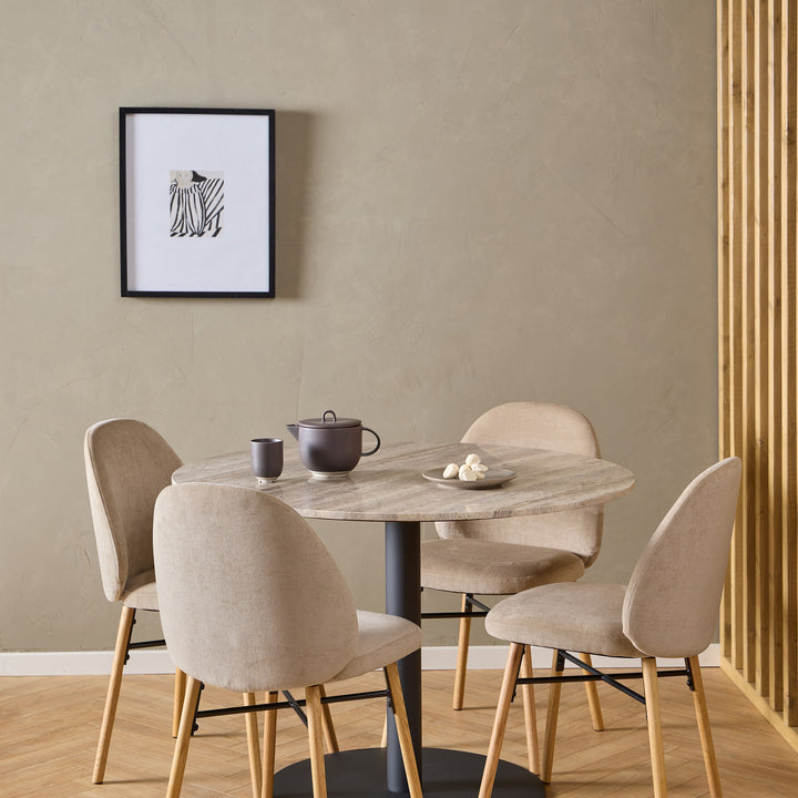 Sophia spisestoler i beige ved rundt travertinbord i spisekrok med beige vegg og eikespiler