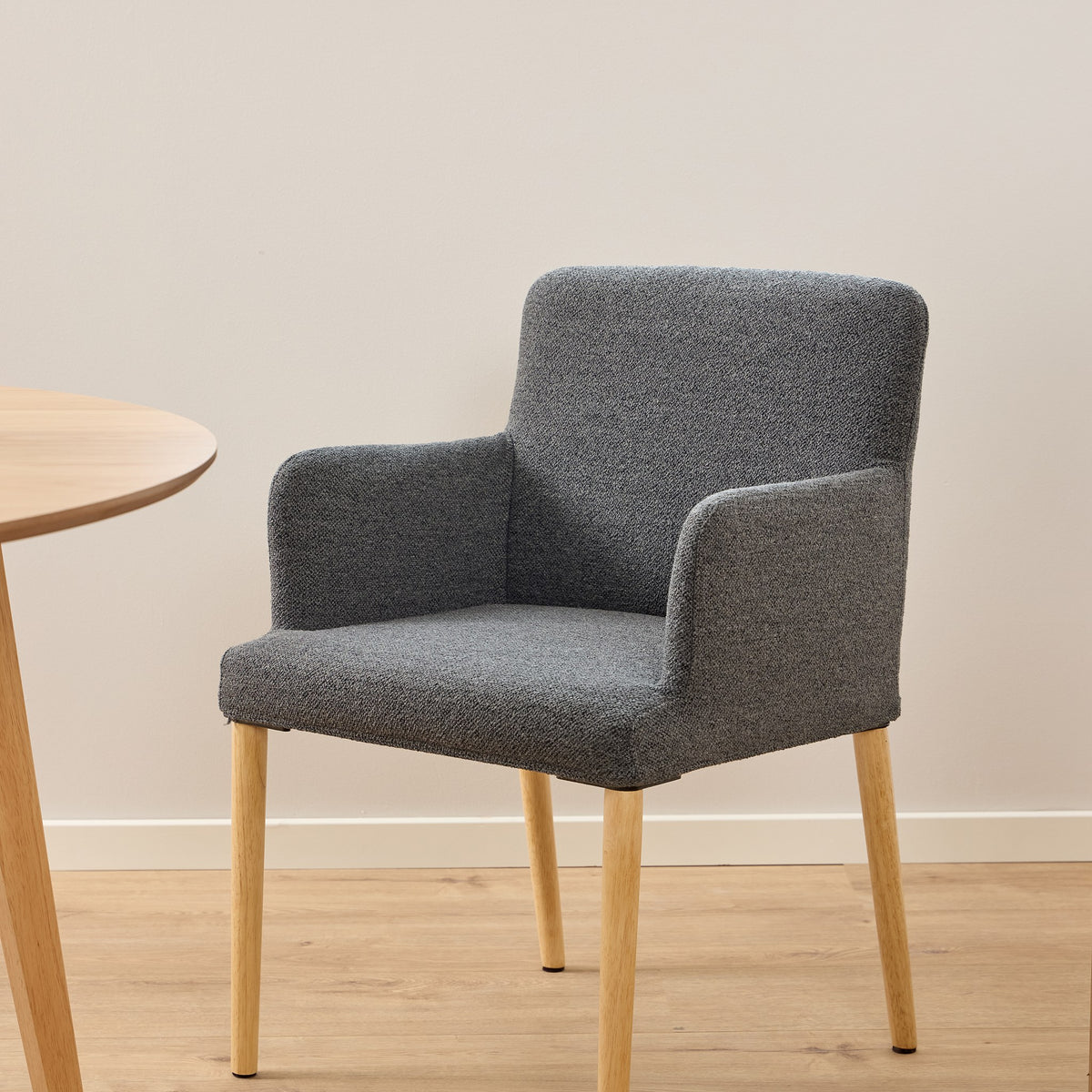 Zoe spisestol i grå strukturstoff med eikeben, ved lyst rundt spisebord