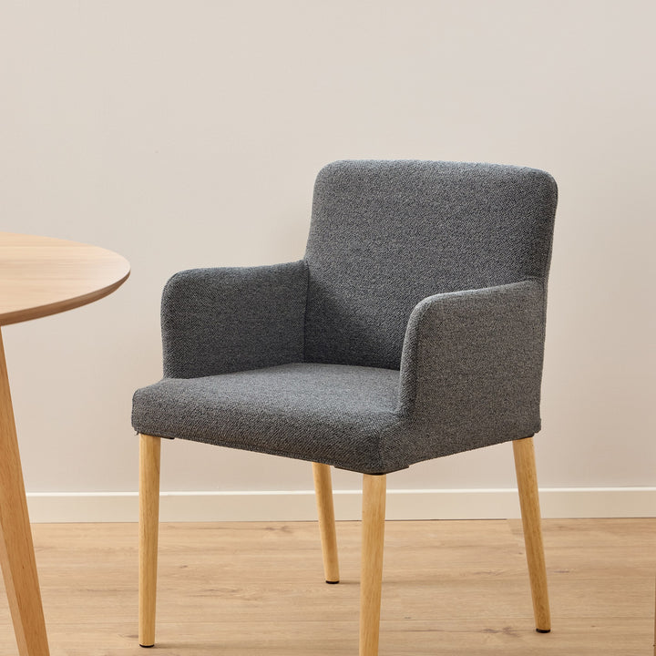 Zoe spisestol i grå strukturstoff med eikeben, ved lyst rundt spisebord