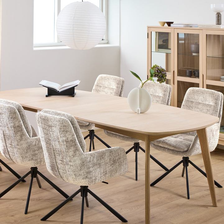 Edgar spisestoler i beige chenille rundt eikebord i lys spisestue med vitrineskap og rislampe