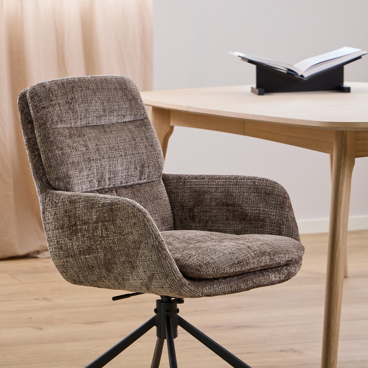 Edgar spisestol i melert brun chenille med svingbar fot, ved lyst eikebord og beige gardin