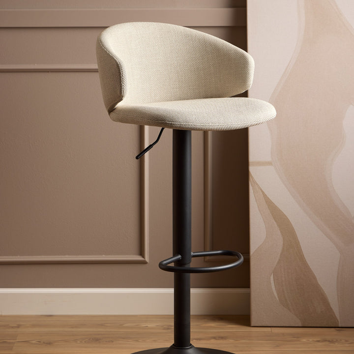 Ella barstol i beige bouclé med svingbar sort fot, mot beige panelvegg