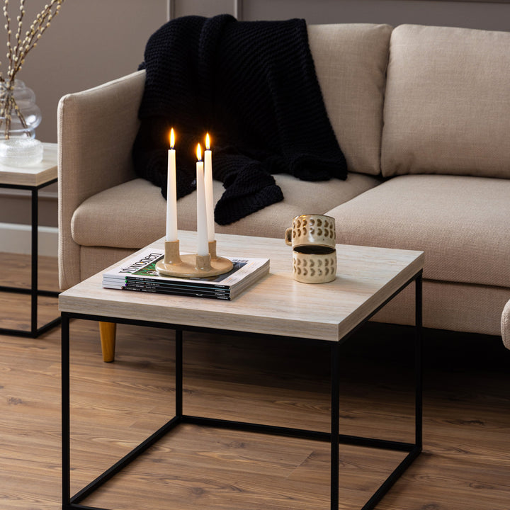 Barossa sofabord med lys travertinplate og sort ramme, foran beige sofa