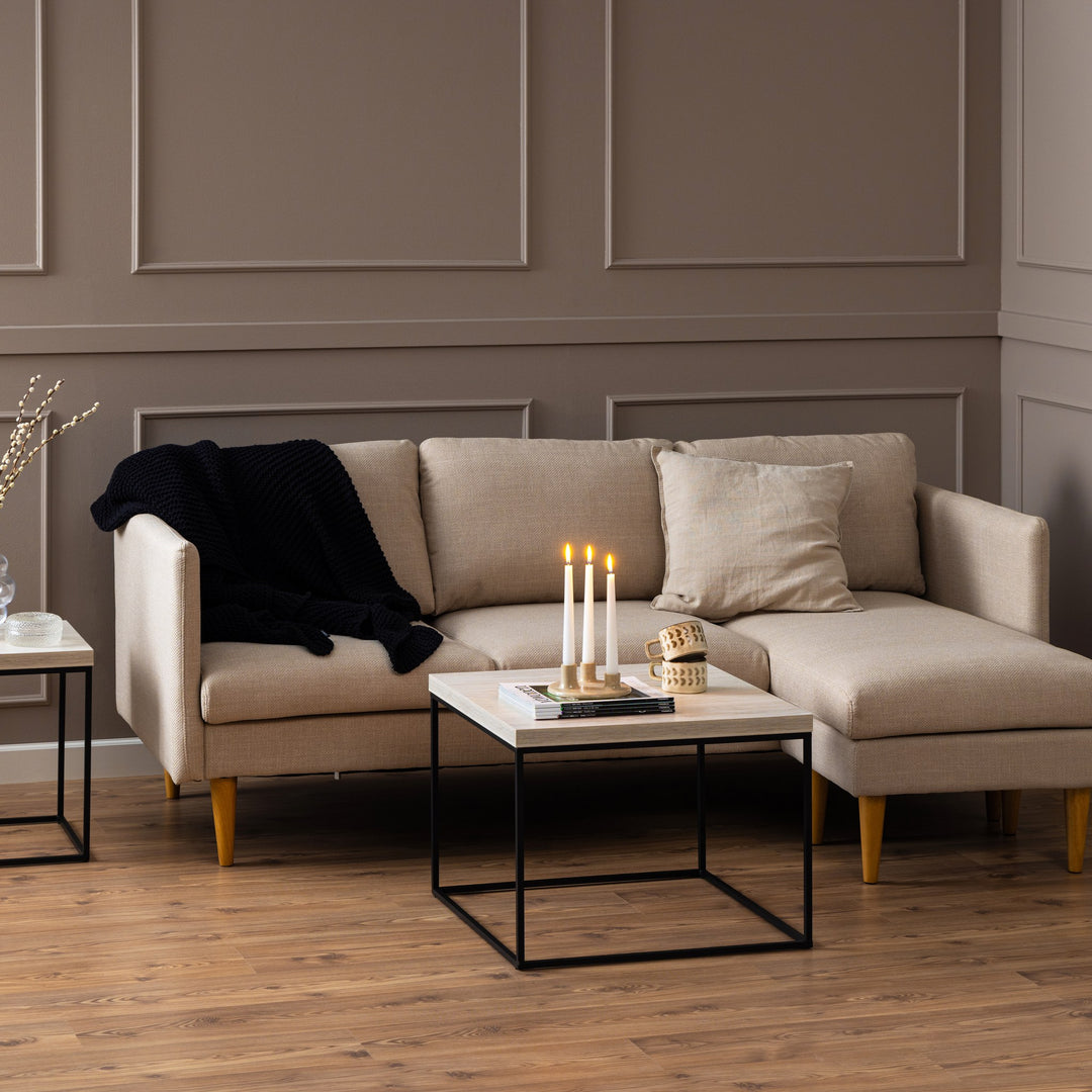 Barossa sofabord med lys travertinplate og sort ramme i beige stue med sofa, lys og krus