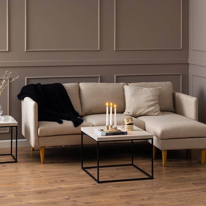 Barossa sofabord med lys travertinplate og sort ramme i beige stue med sofa, lys og krus