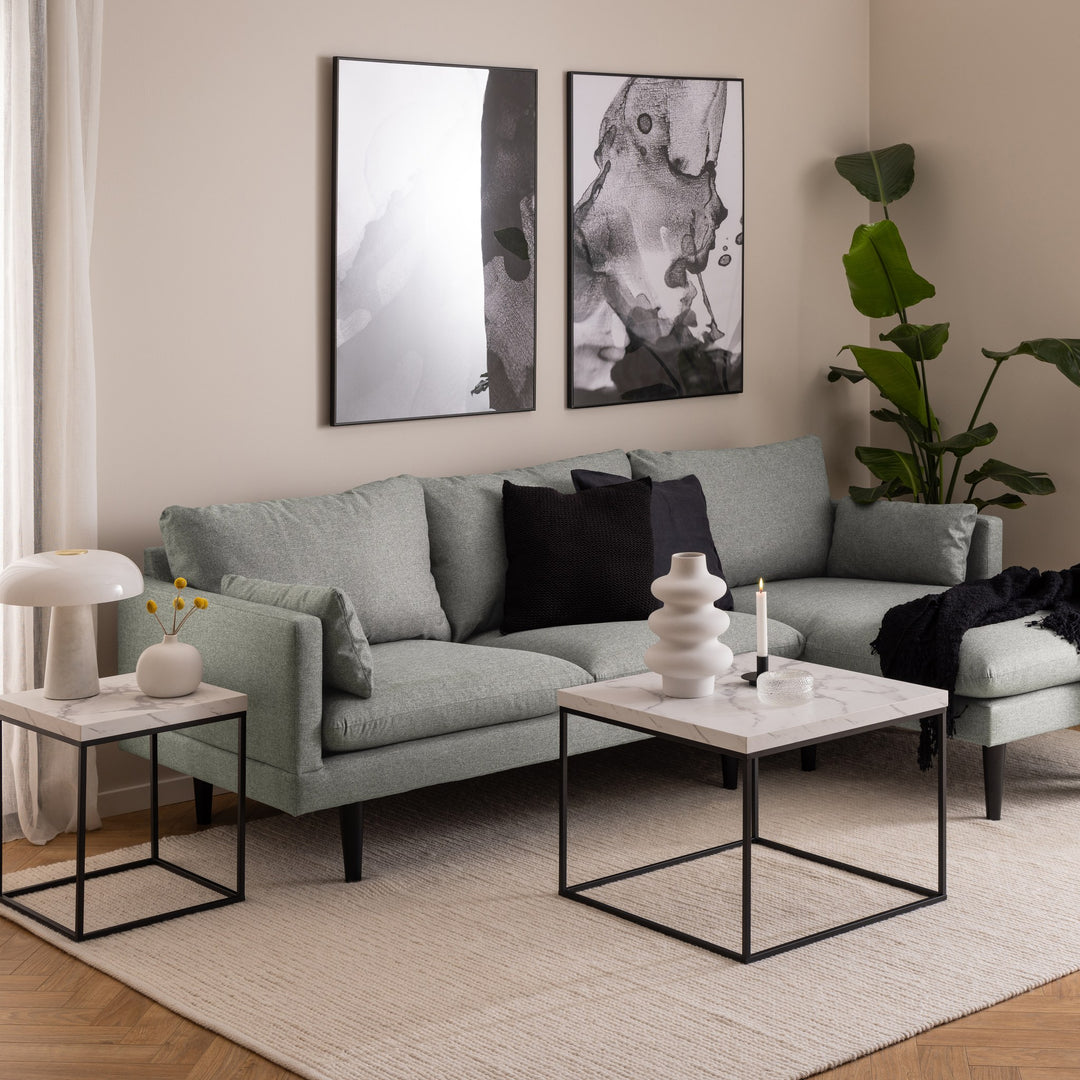 Barossa sofabord med hvit marmorplate og sort ramme i stue med grå sofa og bilder på vegg