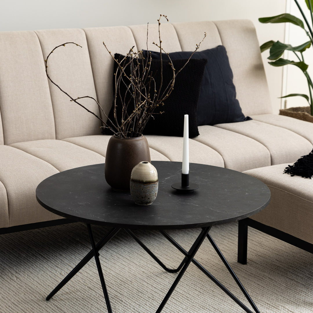 Wyre sofabord med mørk steinplate og tynne sorte ben, foran beige sofa