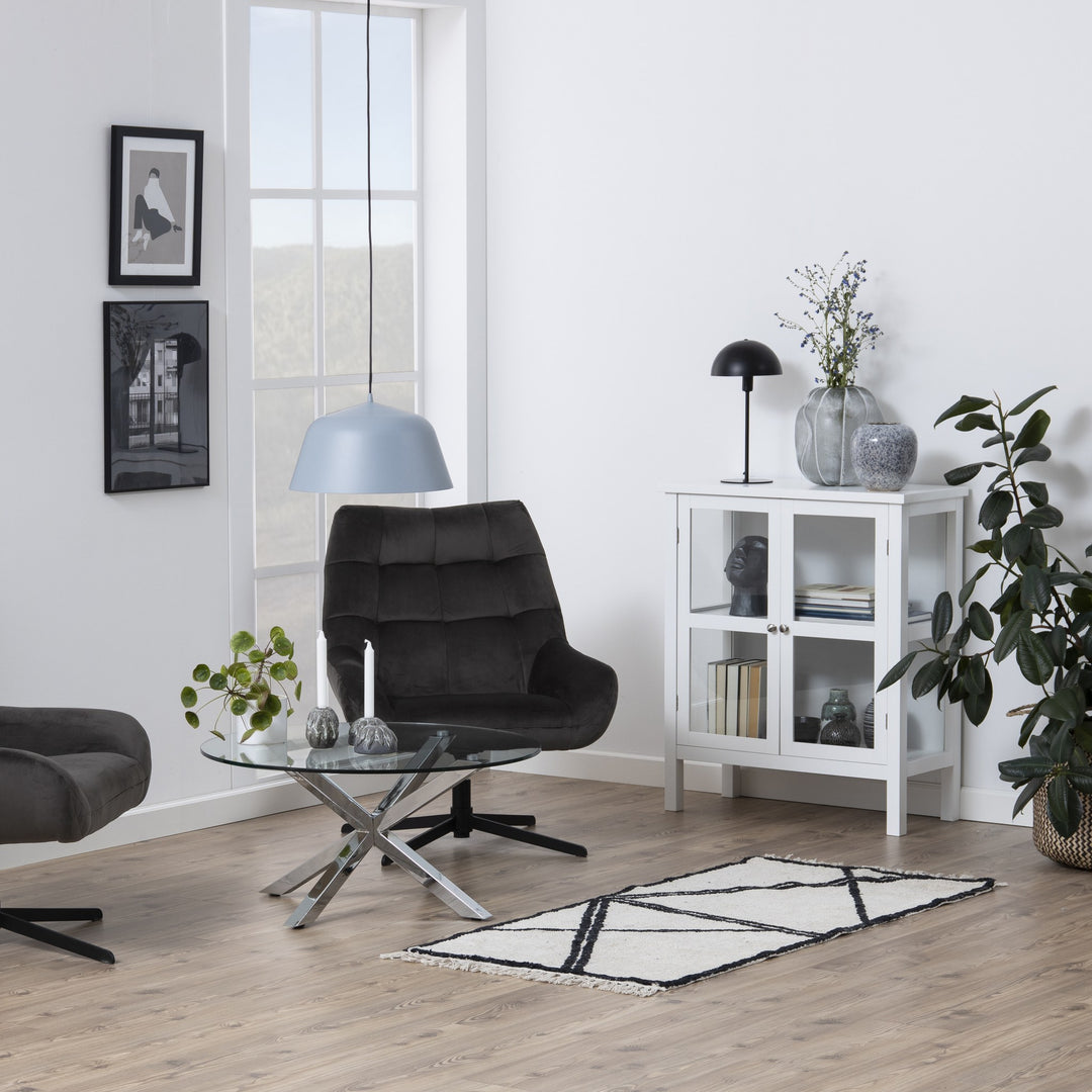 Heaven sofabord med rund glassplate og kromben i stue med sort lenestol og planter