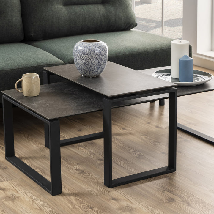 Katrine sofabord med grå keramikkplate og sort ramme foran grønn sofa, med vase og lys