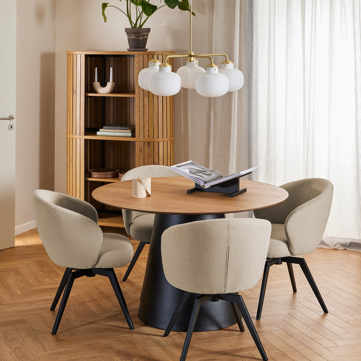 Colima bokhylle i eik i spisestue med rundt bord, beige stoler og grønn plante.