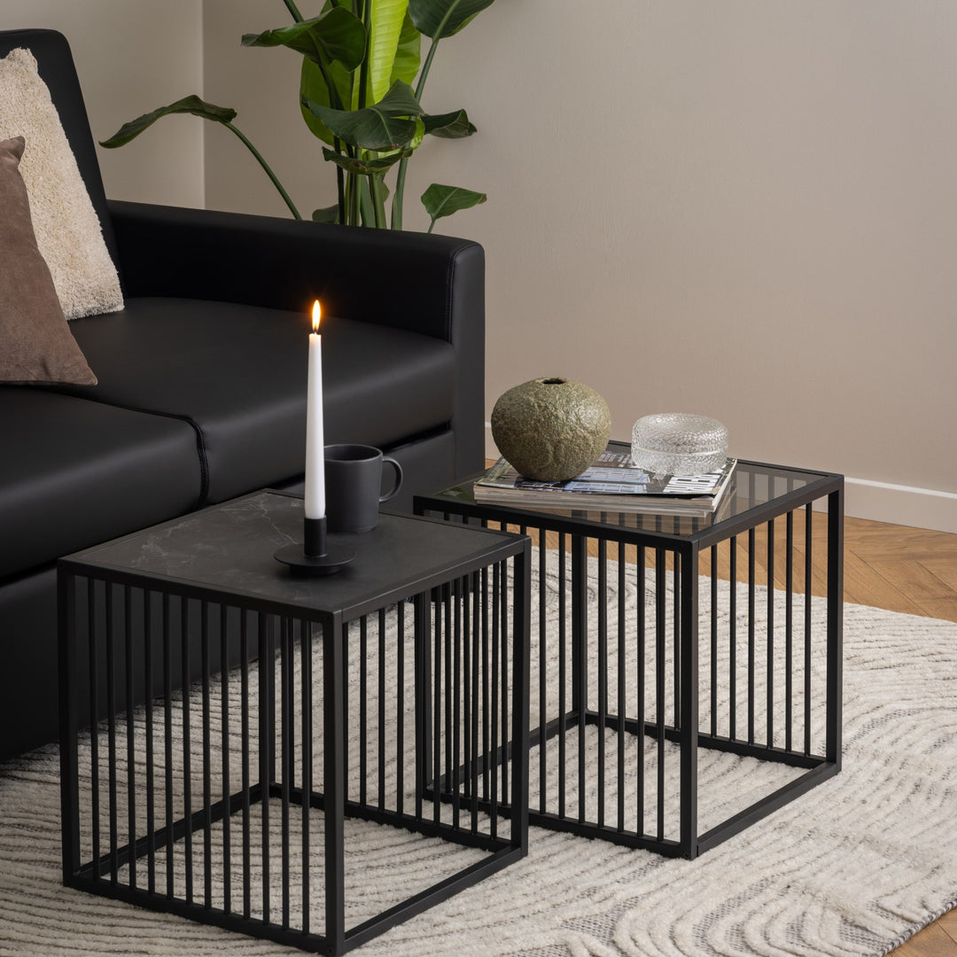 Strington hjørnebord, to sorte settbord på lys rye med lys, kopp og bøker ved sort sofa