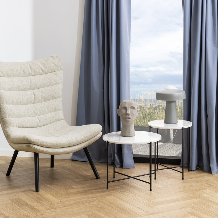 Avila sidebord i hvit marmor i stue med beige lenestol og bordlampe ved vindu