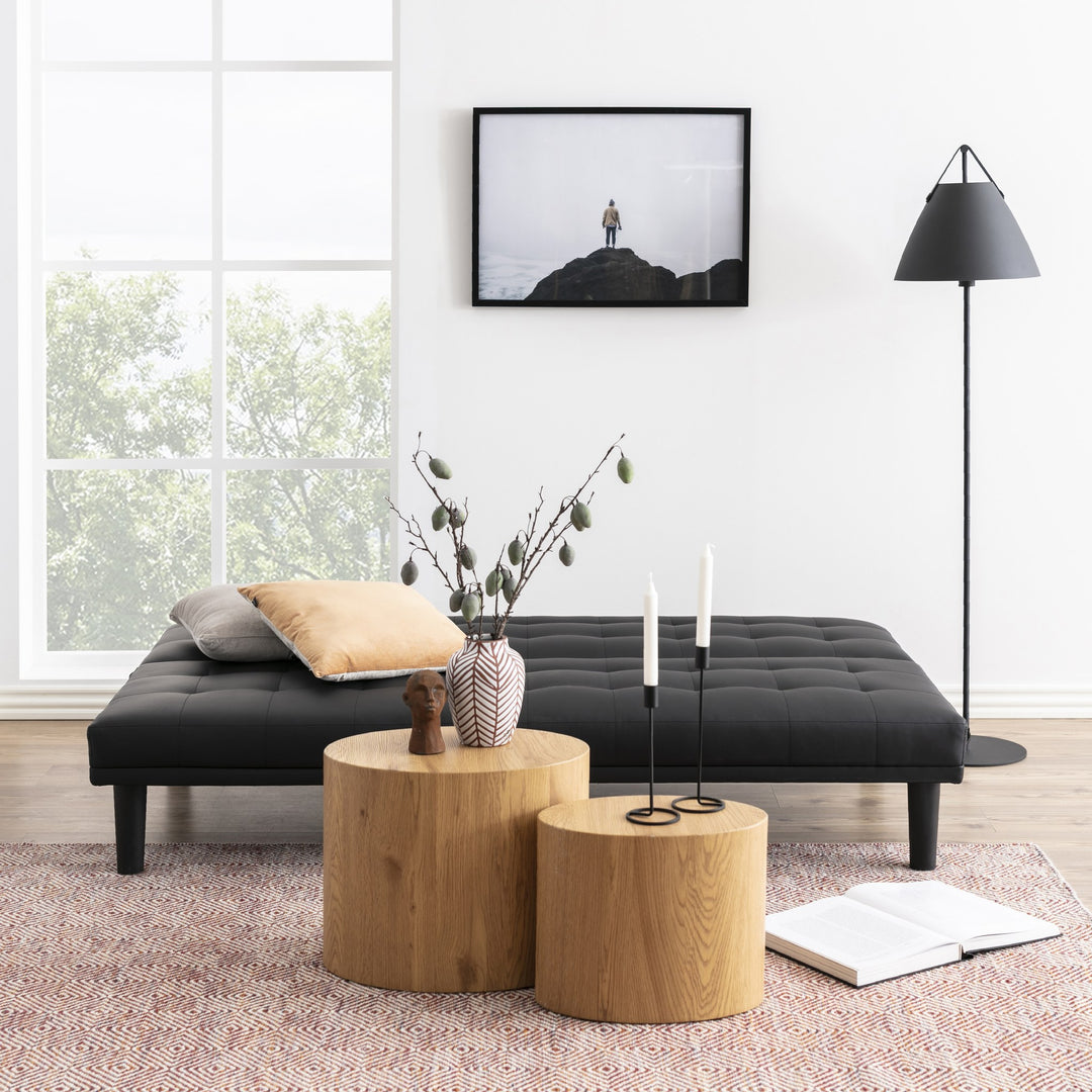 Mice sidebord som ovale søyler i lys eik, to bord ved sort daybed med vase og lys.