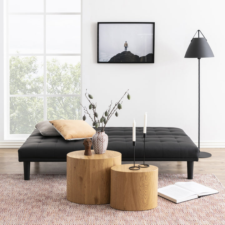 Mice sidebord som ovale søyler i lys eik, to bord ved sort daybed med vase og lys.