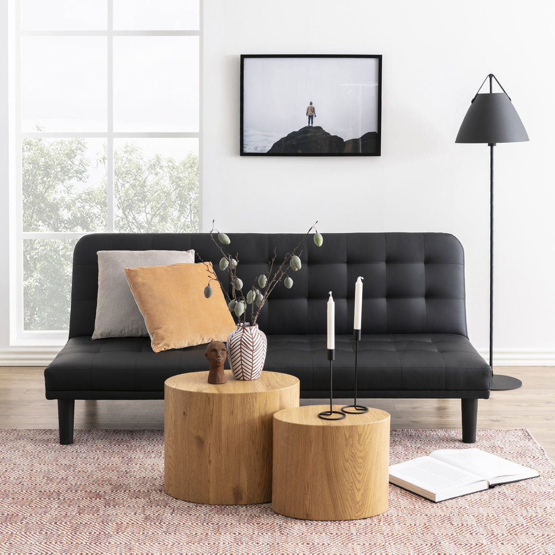 Mice sidebord i villeik, to runde bord foran sort sovesofa med vase og lysestaker