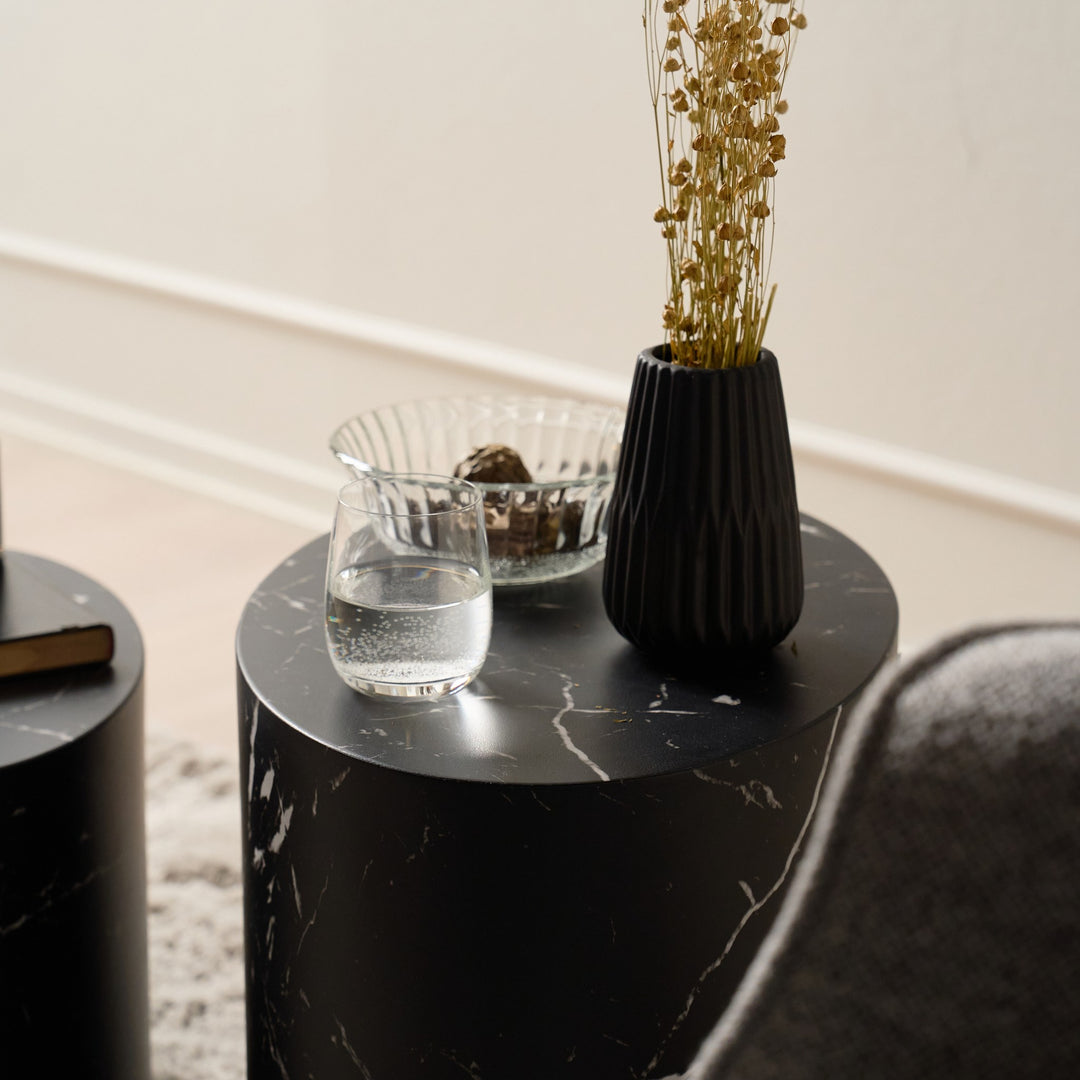 Mice sidebord i sort marmor med vannglass, skål og sort vase med tørkede blomster