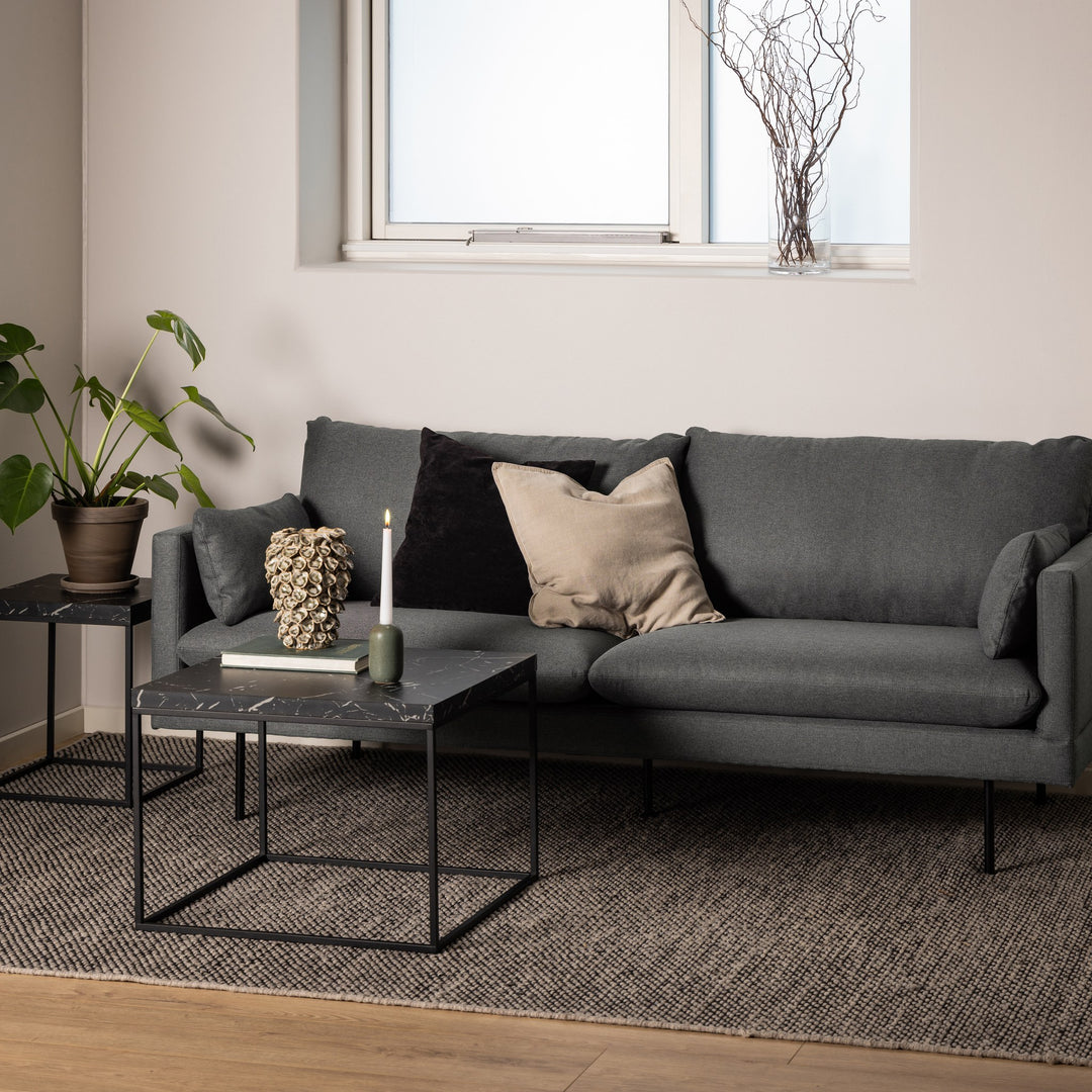 Barossa sidebord med sort marmorplate, to settbord ved grå sofa med lys, bøker og plante