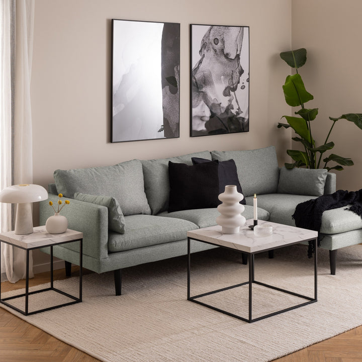 Barossa sidebord i hvit marmor med sort ramme ved grågrønn sofa med lampe og kunst