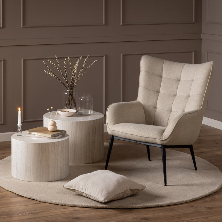 Dice sidebord i beige travertinlook ved beige lenestol med gråbrun panelvegg