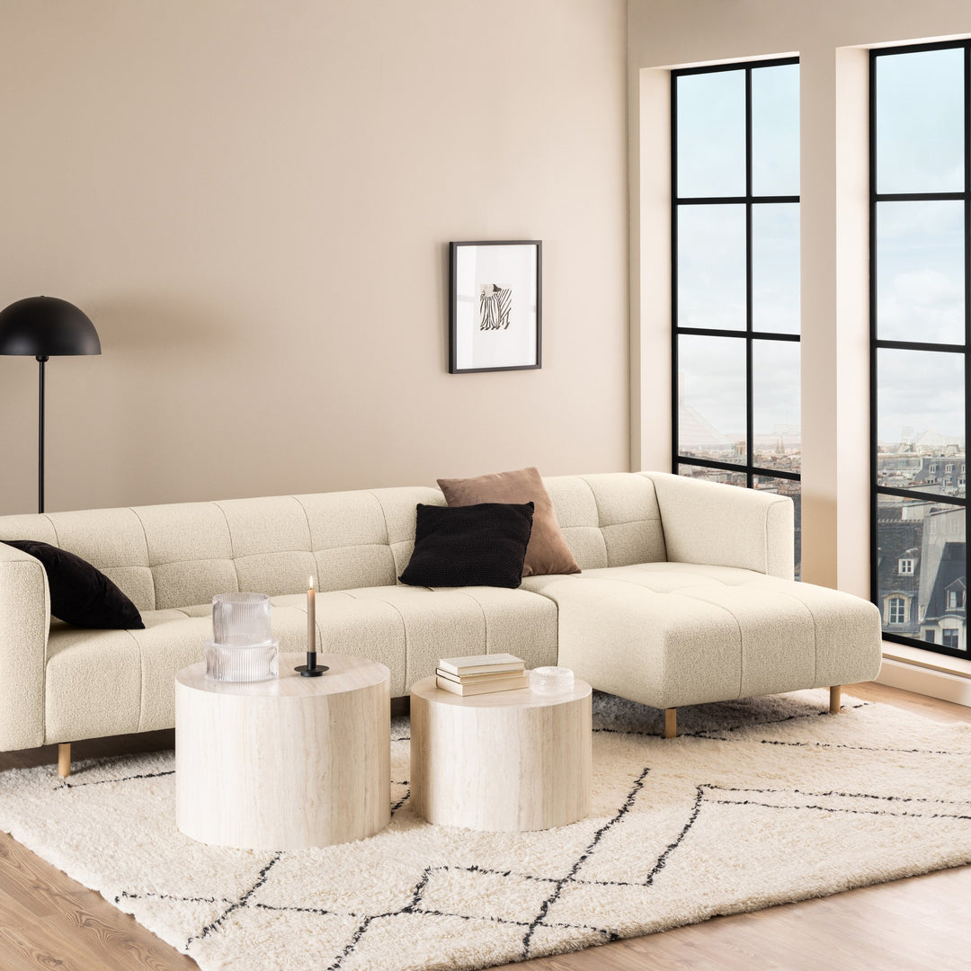 Dice sidebord i beige travertinlook i stue med kremhvit bouclésofa og store vinduer